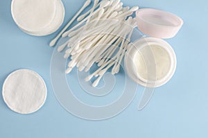 Ear sticks and cotton pads on pastel blue background. Makeup removal and skin care concept.