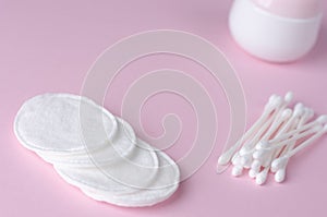 Ear sticks and cotton pads on pastel pink background.