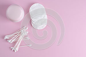 Ear sticks and cotton pads on pastel pink background. Makeup removal and skin care concept.