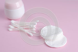 Ear sticks and cotton pads on pastel pink background. Makeup removal and skin care concept.