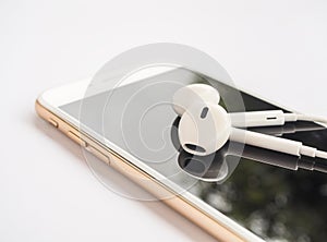 Earbuds on top of smartphone screen isolate