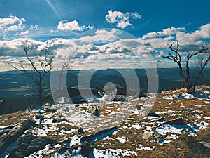 Early cold and misty morning at hoarfrost grass on mountain, view over frozen grass and boulders to trees and hill.l.