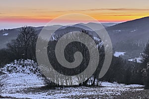 Zimná hmlistá horská krajina s krásnou farebnou oblohou pri západe slnka
