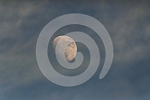 An early evening moon among light clouds