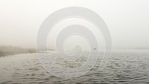 Early foggy morning in river. Fishermens silhouettes on boats.