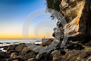 Early morning bather at ocean baths against blue sky and rocky coastline