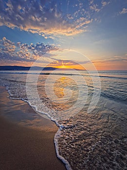 Early morning on the beach with a peaceful view to the sunrise above the sea. Calm seascape dawn scene, natural background. Summer