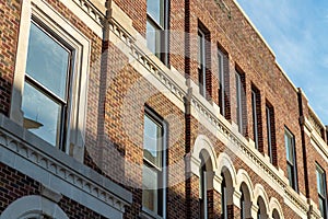 Early morning brick facade with visible windows and white accent paint on side of structure or building in downtown city