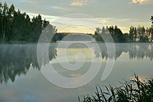 Early morning on the lake with calm foggy water