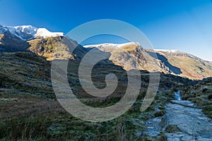 Early morning light and shadow over mountains and snow. Snow capped mountains, Y Garn and Foel Goch, Lake or Llyn Idwal in