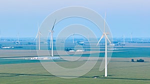 Early morning over farmland with wind farm turbines in hazy air aerial