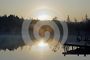 Early in the morning over the lake. Light fog and first rays of sunlight. September.