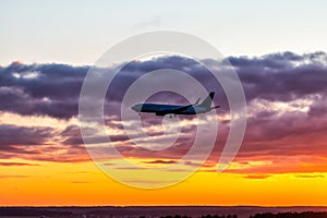 Early morning passenger airliner landing against the background of a colorful dawn sky. Jet plane silhouette