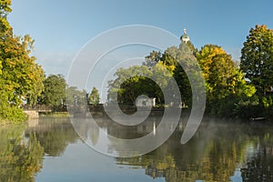 Early morning by a river with mist and autumn colored trees