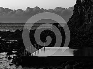 Early morning at the seapool with rocks and headland in monochrome