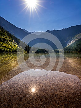 The early morning sun casting its rays over Avalance Lake in Glacier National Park photo