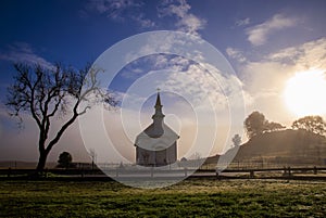 Early morning sun, mist, and fog on small rural church in field photo