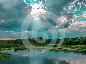 Early morning sun rays shining through opening in clouds on to lake surface at sweetwater wetlands.  Gainesville, Florida photo