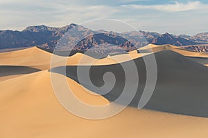 Early Morning Sunlight Over Sand Dunes And Mountains At Mesquite flat dunes, Death Valley National Park, California USA