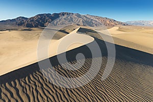 Early Morning Sunlight Over Sand Dunes And Mountains At Mesquite flat dunes, Death Valley National Park, California USA