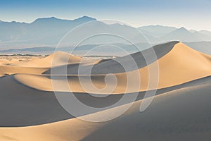 Early Morning Sunlight Over Sand Dunes And Mountains At Mesquite flat dunes, Death Valley National Park, California USA