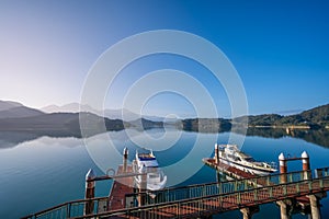 In the early morning sunshine, the dock, lake and mountains are all in sight.