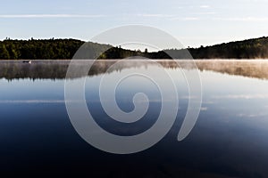 Early morning at Swan Lake in Maine with fog on the surface on a calm late spring day