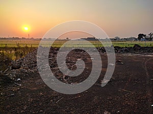 early morning view of a farm field with golden shining sunrise