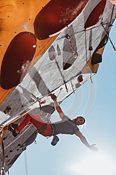 Early morning workouts. One Caucasian man professional rock climber practicing alone at training center in sunny day