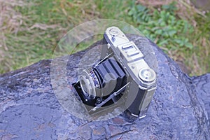 Early 1940Ã¢â¬â¢s Folding Film Camera with bellows and lens extended to front of camera and situated on a rusty canon photo