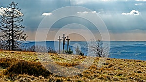 Glistening meadow and sunrays through clouds with Golgotha crosses on Kreuzberg mountain in Rhoen, Germany photo