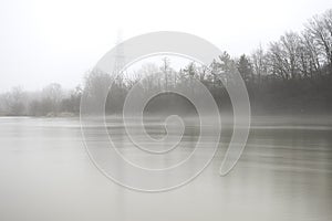 Early spring river bank and electrical tower fading by rising mi