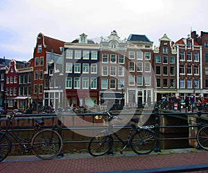 Early spring scene in Amsterdam city. Tours by boat on the famous Dutch canals. Cityscape with canal houses in Holland,