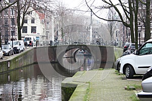 Early spring scene in Amsterdam city. Tours by boat on the famous Dutch canals. Cityscape with canal houses in Holland,