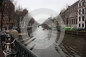 Early spring scene in Amsterdam city. Tours by boat on the famous Dutch canals. Cityscape with canal houses in Holland,