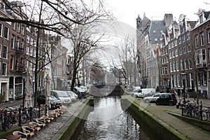 Early spring scene in Amsterdam city. Tours by boat on the famous Dutch canals. Cityscape with canal houses in Holland,