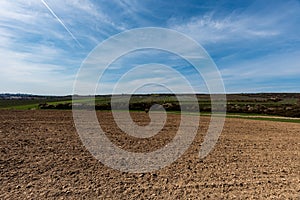 Early springtime countryside with fields, meadows, vineayards, blossoming trees, smaller village and blue sky with clouds