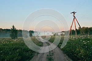 Early summer morning in the country. Fog over field and road