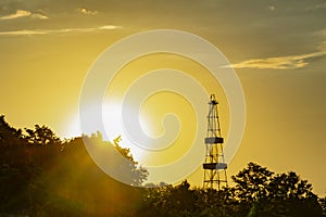 Early sunset over forest and huge high tall observation tower. Ukrainian view, yellow sunrise, cloudy sky