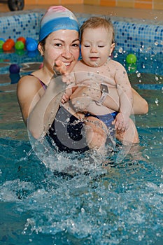 Early swimming coach training to swim baby in indoor pool