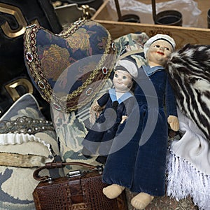 early twentieth century rag dolls dressed as sailors among clothes at an antique market