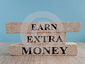 Earn extra money text written on brick blocks. Concept of financial planning Make more extra money from parttime side hustle or photo