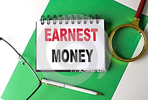 EARNEST MONEY text on notebook on green paper