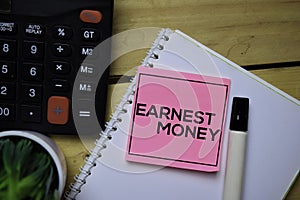 Earnest Money write on sticky note with wooden table background