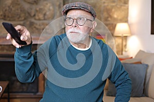 Earnest senior man watching tv with serious expression