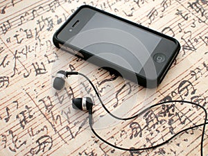 Earphones and phone on music sheet background