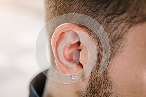 Earring in the male ear. Piercing Part of the body