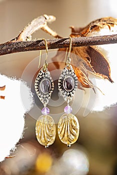 earrings with amethyst and glass bead, hanging on natural background