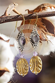 earrings with amethyst and glass bead, hanging on natural background