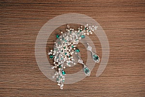 Earrings with a large green stone and a decoration of white beads on a brown background.